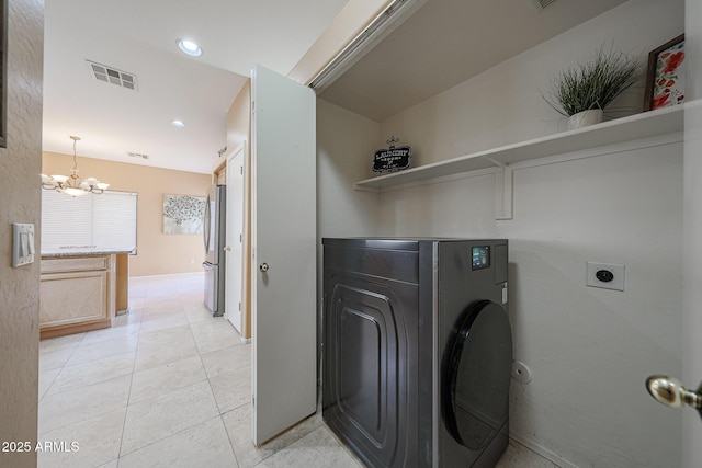 clothes washing area featuring laundry area, visible vents, light tile patterned floors, a chandelier, and washer / dryer