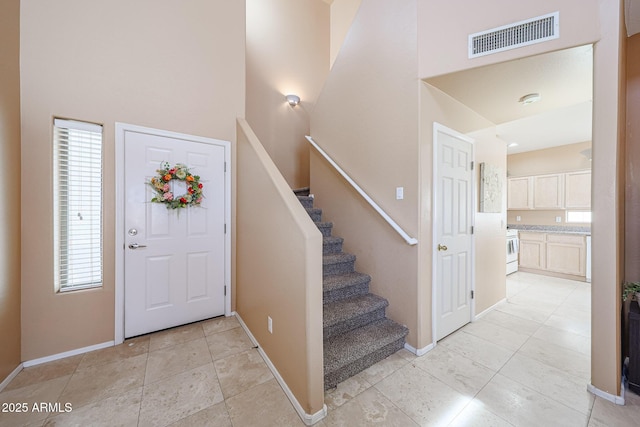 foyer with baseboards, a high ceiling, stairs, and visible vents