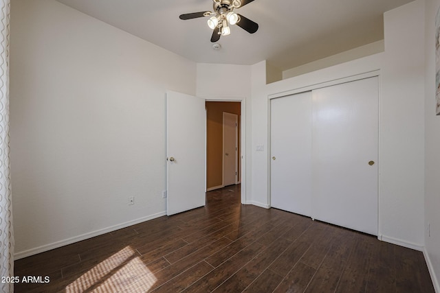unfurnished bedroom featuring baseboards, dark wood finished floors, and a closet