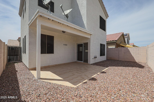 rear view of property with a fenced backyard, stucco siding, and a patio area
