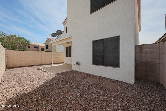 rear view of property with a fenced backyard, stucco siding, and a patio area