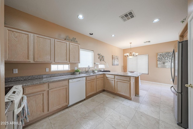 kitchen featuring visible vents, white dishwasher, range, freestanding refrigerator, and light brown cabinets