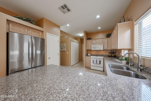 kitchen featuring visible vents, a sink, light brown cabinets, recessed lighting, and white appliances