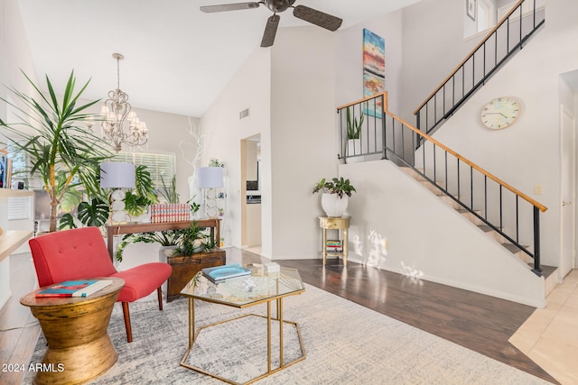 living room with hardwood / wood-style floors, ceiling fan with notable chandelier, and high vaulted ceiling