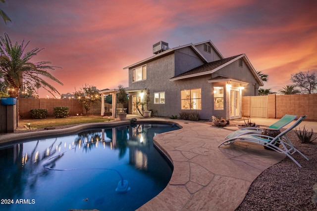 pool at dusk with a patio and central AC