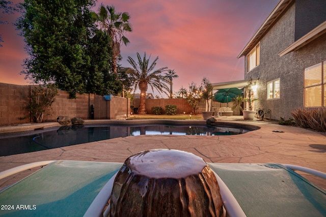 pool at dusk with a patio area