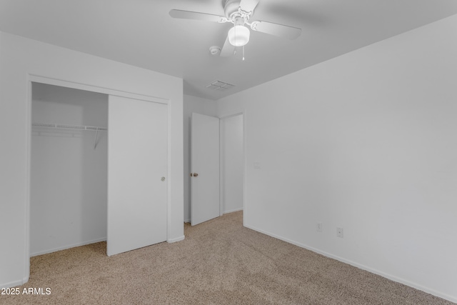 unfurnished bedroom featuring light carpet, a closet, and ceiling fan