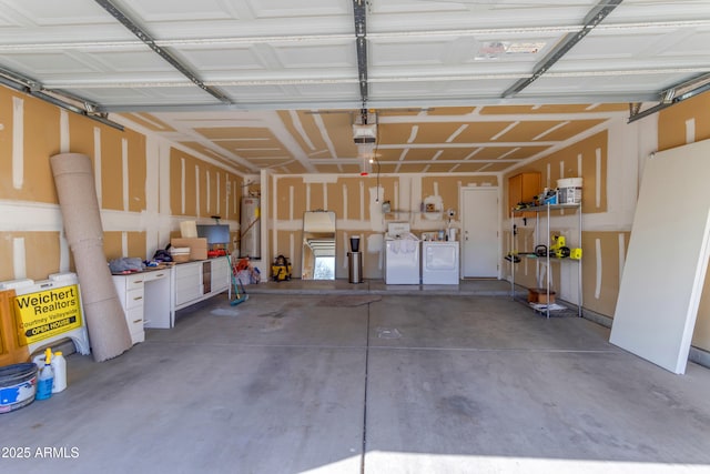 garage with washing machine and clothes dryer, a garage door opener, and gas water heater