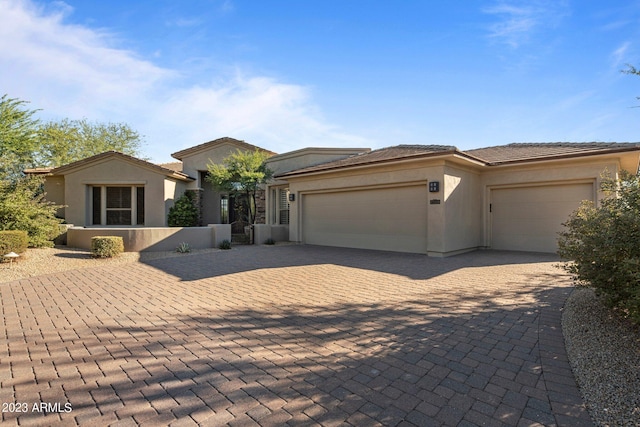 view of front facade featuring a garage, decorative driveway, stucco siding, and a tiled roof