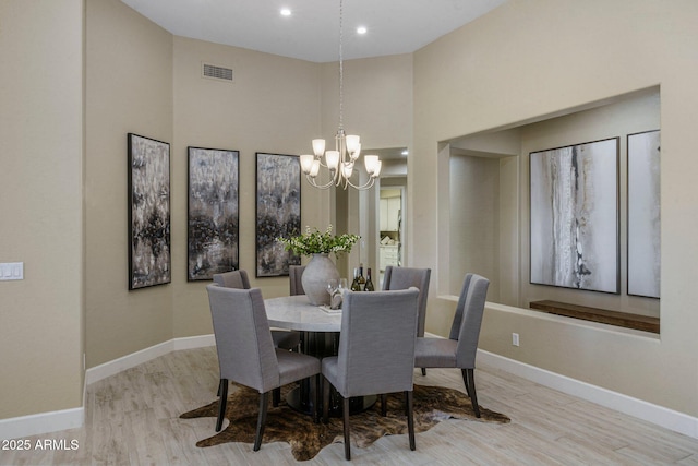 dining space with a chandelier, wood finished floors, baseboards, recessed lighting, and a towering ceiling
