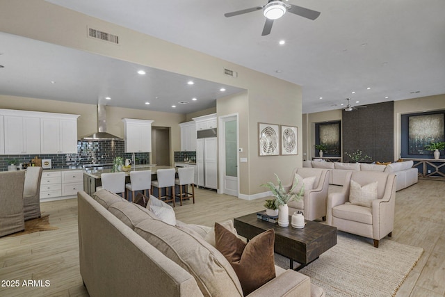 living room with ceiling fan, light wood finished floors, recessed lighting, and baseboards