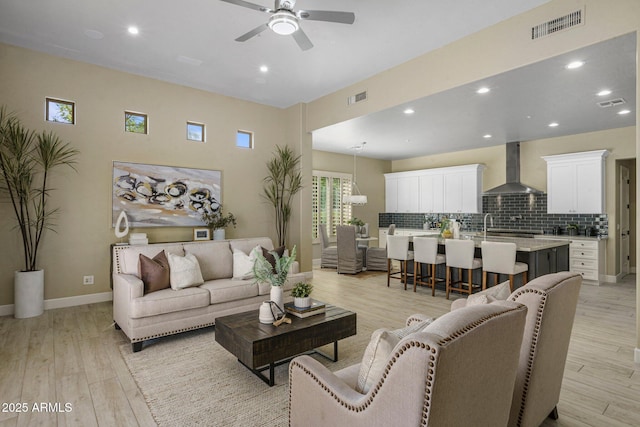 living room with ceiling fan, light wood-style floors, recessed lighting, and baseboards