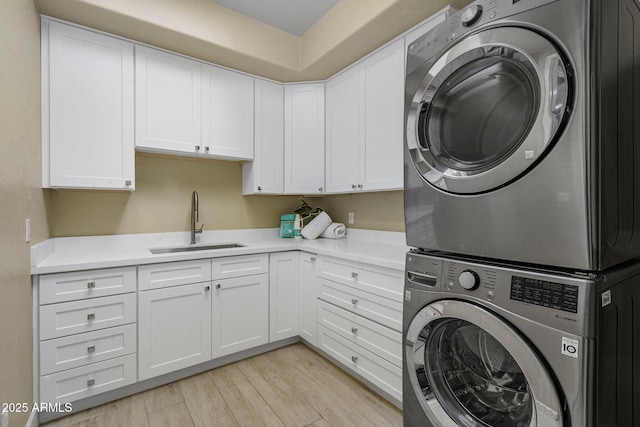 laundry room with stacked washer / dryer, cabinet space, and light wood-style floors