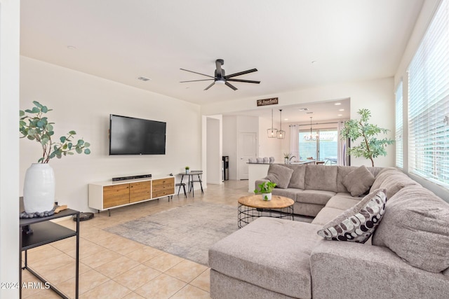 tiled living room with ceiling fan with notable chandelier