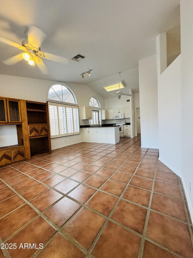 unfurnished living room with ceiling fan, lofted ceiling, and tile patterned flooring