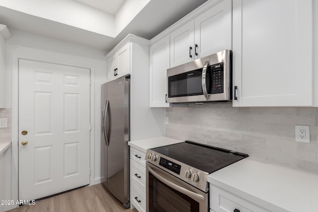 kitchen with tasteful backsplash, light countertops, light wood-style flooring, appliances with stainless steel finishes, and white cabinetry