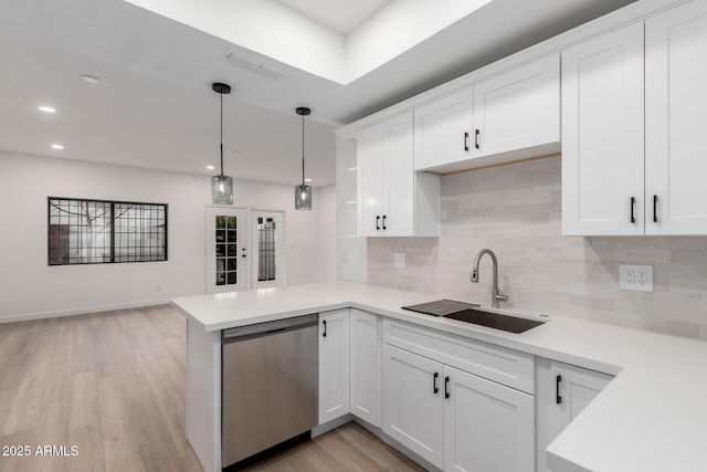 kitchen featuring a sink, stainless steel dishwasher, light wood-style floors, a peninsula, and light countertops