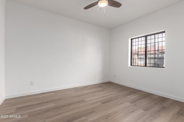 empty room featuring ceiling fan, baseboards, and wood finished floors