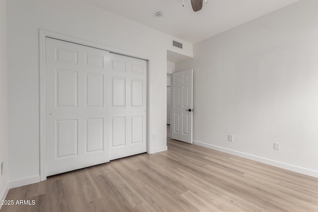 unfurnished bedroom featuring light wood-type flooring, visible vents, a ceiling fan, a closet, and baseboards