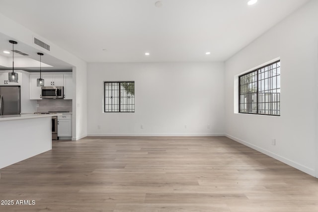 unfurnished living room with a wealth of natural light, recessed lighting, and light wood-style flooring