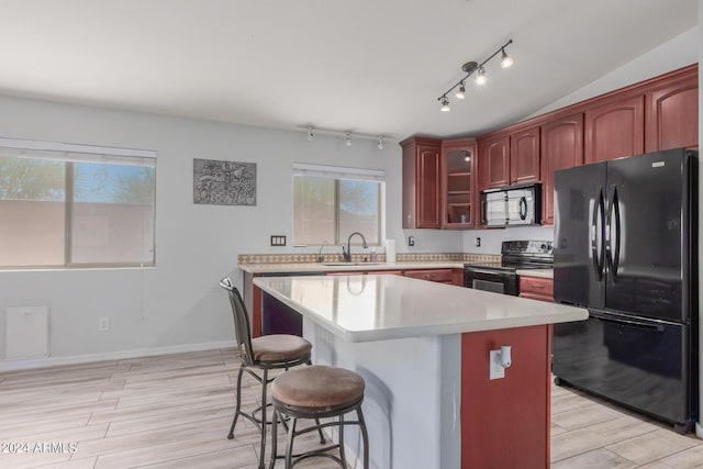 kitchen featuring a wealth of natural light, sink, a breakfast bar, a kitchen island, and black appliances