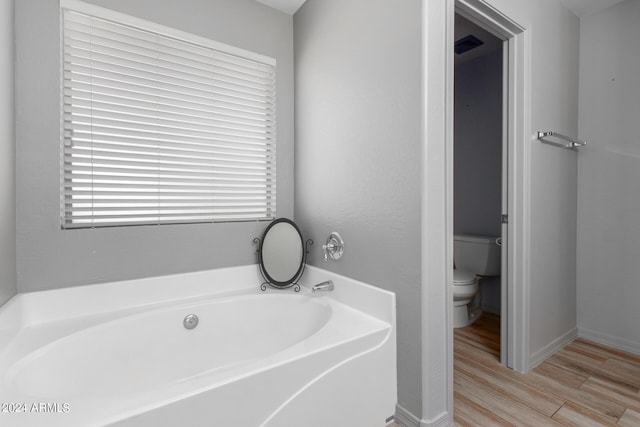 bathroom with hardwood / wood-style flooring, toilet, and a bathing tub