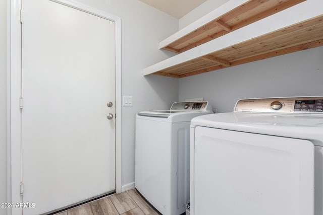 laundry room with washing machine and clothes dryer and light wood-type flooring