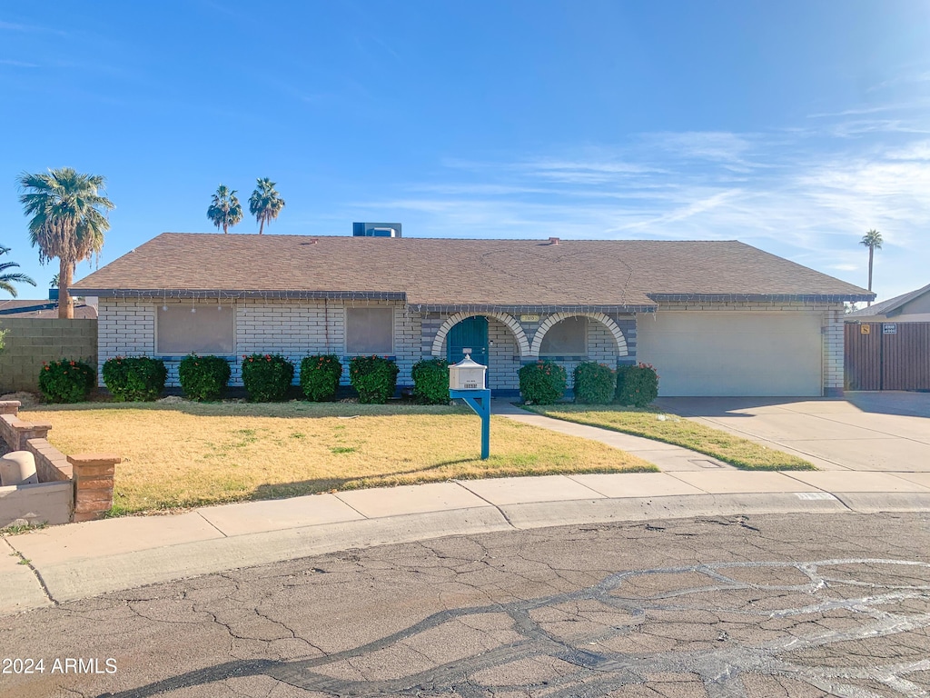 ranch-style home with a garage and a front lawn