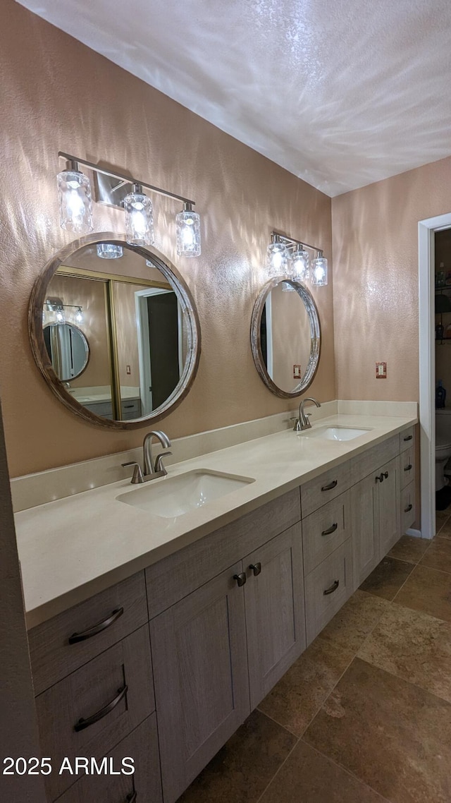 full bathroom featuring a textured wall, a sink, a textured ceiling, and double vanity