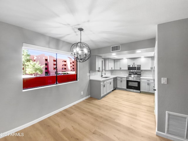 kitchen featuring stainless steel appliances, light wood finished floors, a sink, and visible vents