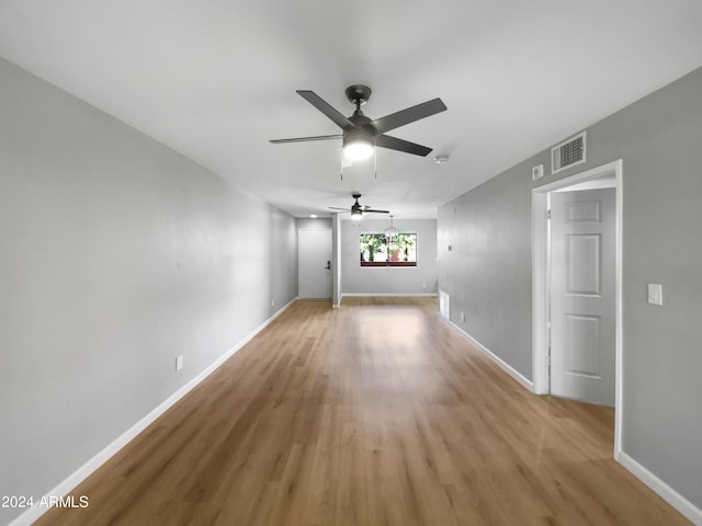 unfurnished living room featuring light wood-style flooring, a ceiling fan, visible vents, and baseboards