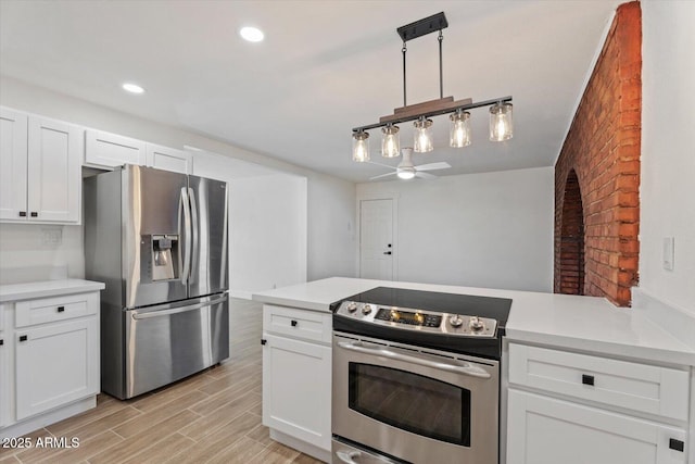 kitchen featuring pendant lighting, appliances with stainless steel finishes, light wood-type flooring, and white cabinets