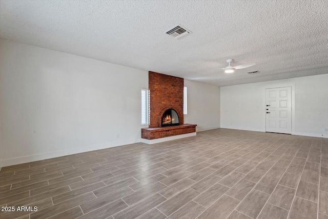 unfurnished living room featuring a textured ceiling, a fireplace, and ceiling fan