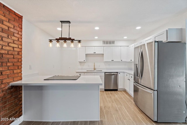 kitchen with sink, appliances with stainless steel finishes, white cabinetry, decorative light fixtures, and kitchen peninsula