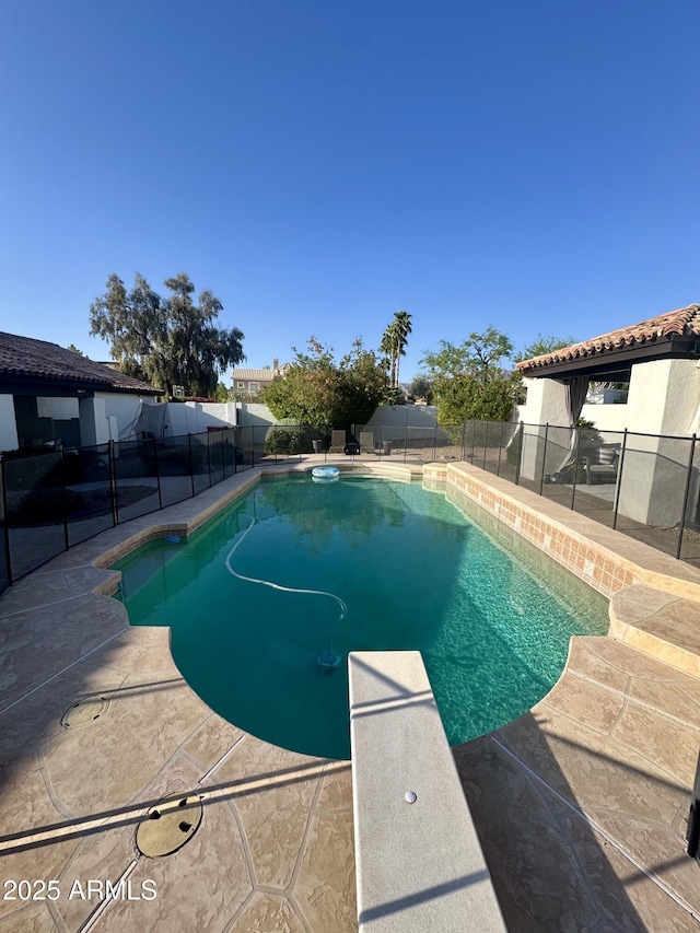 view of swimming pool with a diving board, a fenced backyard, a patio area, and a fenced in pool