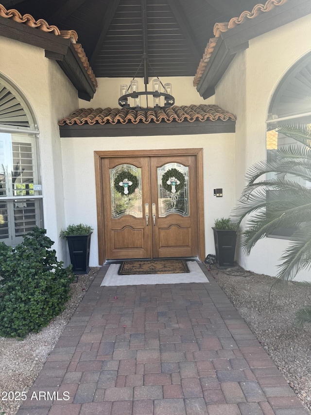 property entrance featuring a tile roof and stucco siding