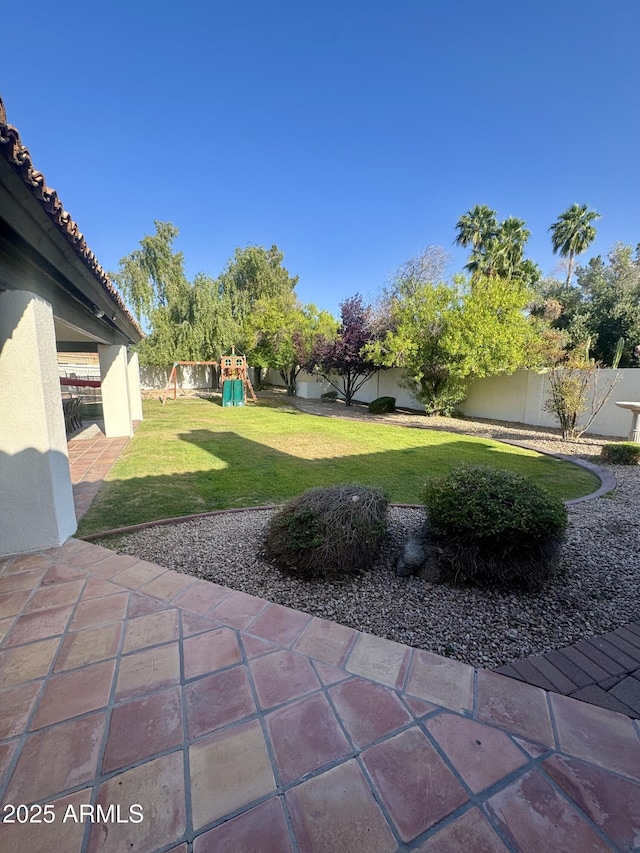 view of yard featuring a playground, a fenced backyard, and a patio area