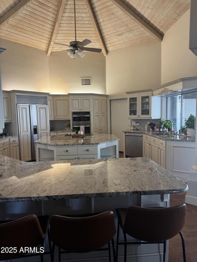 kitchen with wooden ceiling, high vaulted ceiling, a center island, visible vents, and appliances with stainless steel finishes