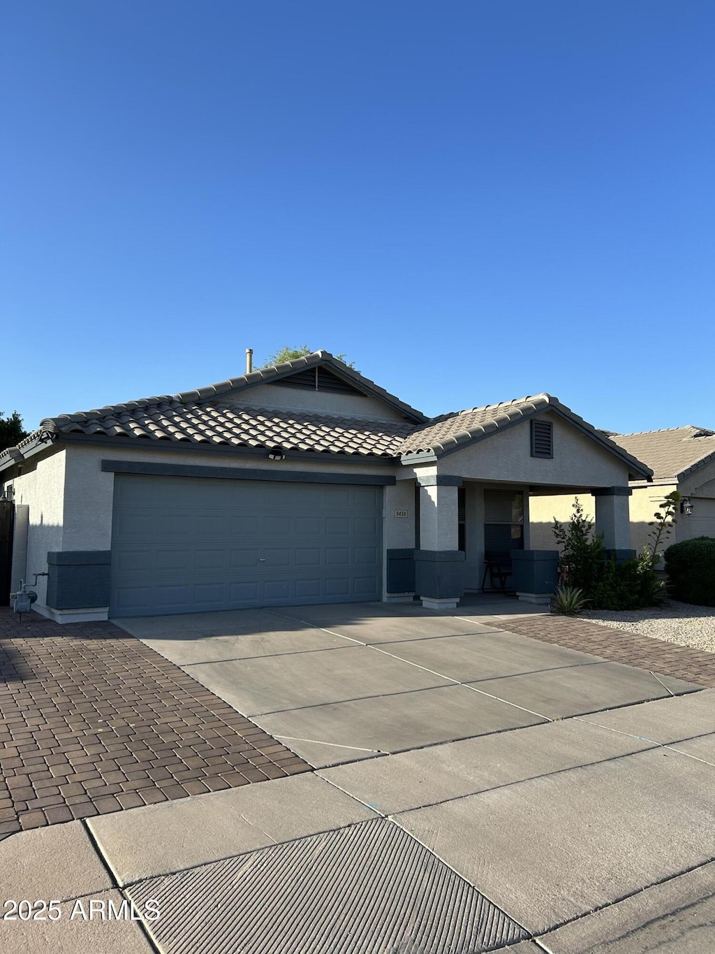 ranch-style home featuring an attached garage, stucco siding, a tile roof, and concrete driveway