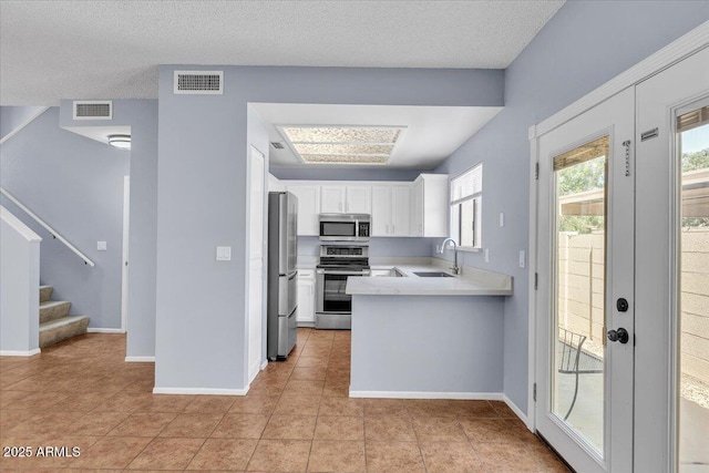 2954 N Oregon St Unit 6, Chandler, AZ 85225 - kitchen with stainless steel appliances, light tile patterned flooring, white cabinetry, light countertops, and a peninsula