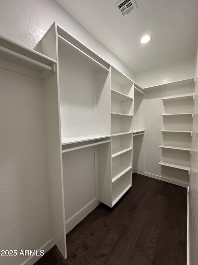 walk in closet with dark wood finished floors and visible vents