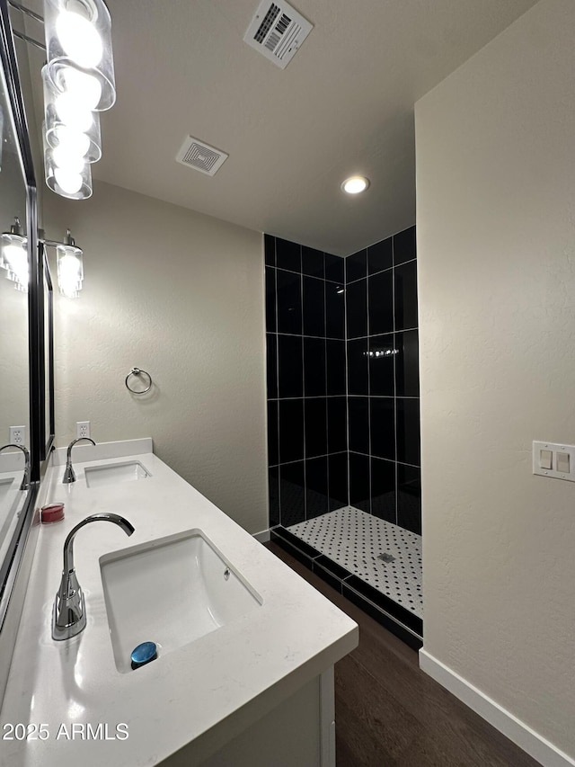 full bath with a tile shower, visible vents, and a sink