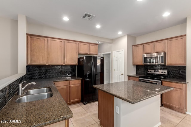 kitchen with visible vents, appliances with stainless steel finishes, light tile patterned flooring, a sink, and dark stone counters