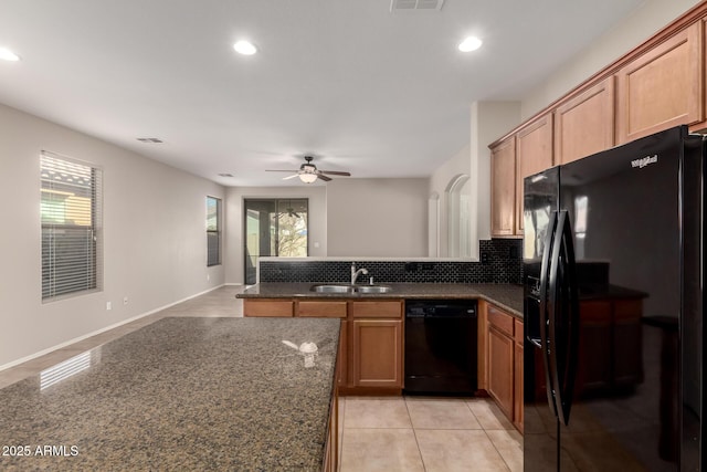 kitchen with a peninsula, a sink, open floor plan, black appliances, and tasteful backsplash