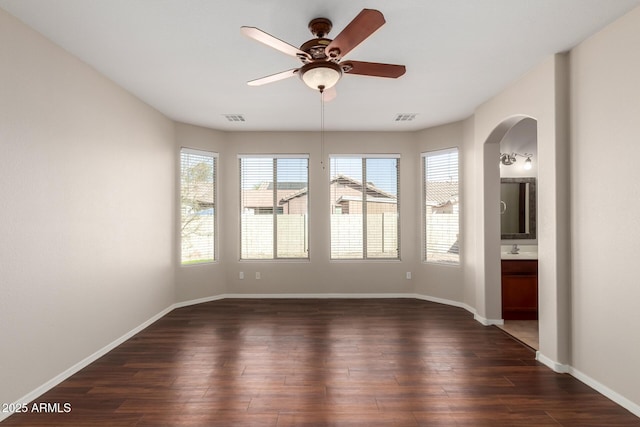 unfurnished room featuring dark wood-style flooring, visible vents, and baseboards