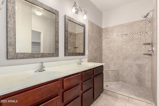 full bath featuring a tile shower, double vanity, and a sink