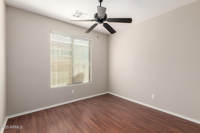 spare room featuring dark wood-type flooring, visible vents, baseboards, and a ceiling fan