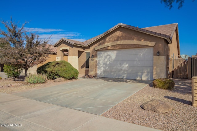 view of front of house with driveway, a tile roof, an attached garage, a gate, and stucco siding