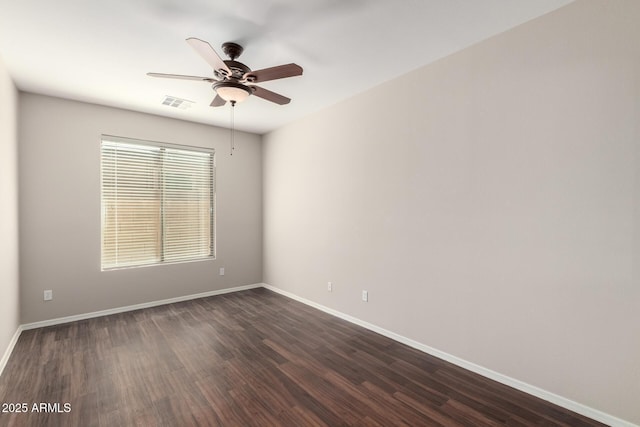 spare room with a ceiling fan, baseboards, visible vents, and dark wood-style flooring