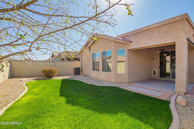 rear view of property with a patio, a fenced backyard, ceiling fan, a yard, and stucco siding